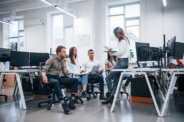 Menschen, die im modernen Büro in der Nähe von Computern sprechen und zusammenarbeiten.