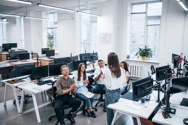 Menschen, die im modernen Büro in der Nähe von Computern sprechen und zusammenarbeiten.