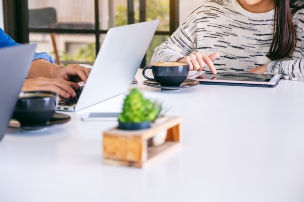 Menschen, die Laptop-Computer und Tablet-PC auf dem Tisch im Büro verwenden und arbeiten