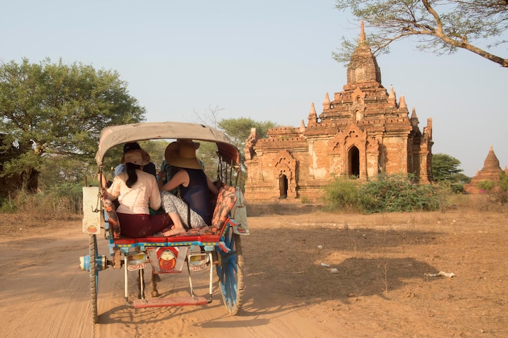 Foto menschen, die mit dem wagen auf einer schotterstraße gegen den tempel fahren