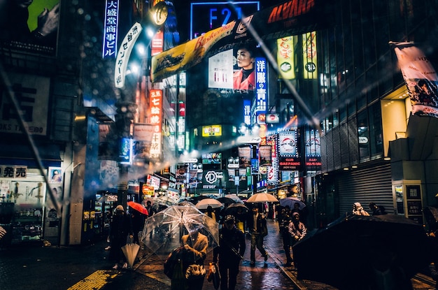 Menschen, die nachts mit Regenschirmen auf einer Stadtstraße spazieren gehen