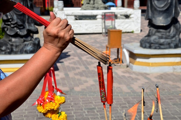Menschen, die Räucherstäbchen und rote Kerzen verbrennen, um Gott am Säulenschrein der Stadt Suphanburi in Suphanburi Thailand zu beten