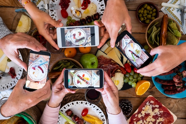 Menschen, die zusammen essen, nehmen ein Essen mit dem Smartphone auf, um es in den sozialen Medien zu teilen