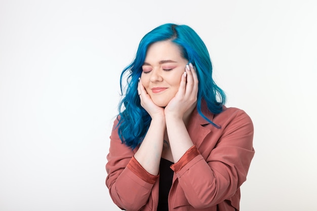 Menschen, Emotionen und Modekonzept - Schönes Mädchen mit blauen Haaren und freudigem Gesicht auf weißer Wand.