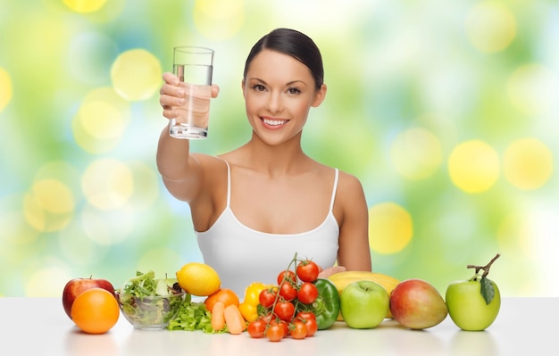 Menschen, Ernährung und vegetarisches Konzept - glückliche asiatische Frau mit gesundem Essen, die ein Glas Wasser auf grünem Hintergrund zeigt