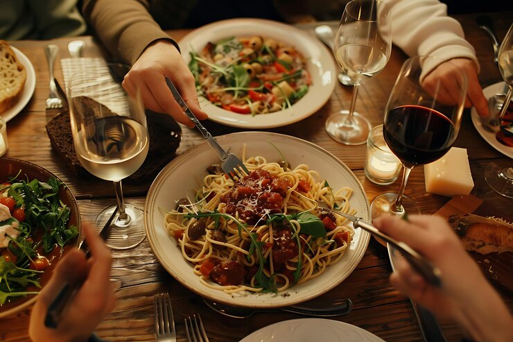Foto menschen essen spaghetti und wein an einem restaurant-tisch mit schüsseln mit essen