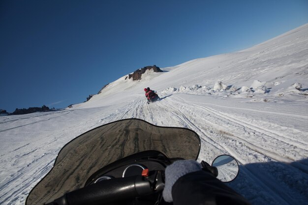 Menschen fahren auf dem Schneefeld auf einem blauen Himmel.