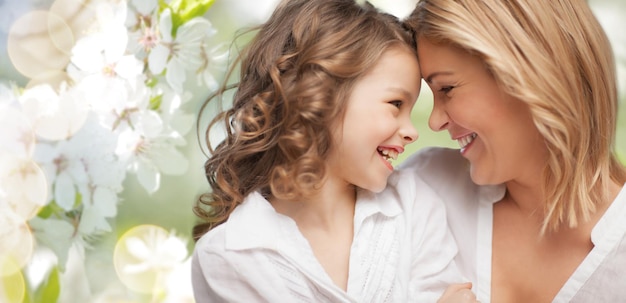 menschen, familie, liebe und harmoniekonzept - glückliche mutter und tochter, die über grünem sommergartenhintergrund kuscheln