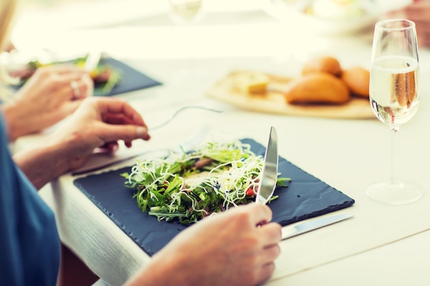 menschen, feiertage, feier und lifestyle-konzept - nahaufnahme einer frau, die salat-vorspeise zum abendessen im restaurant isst