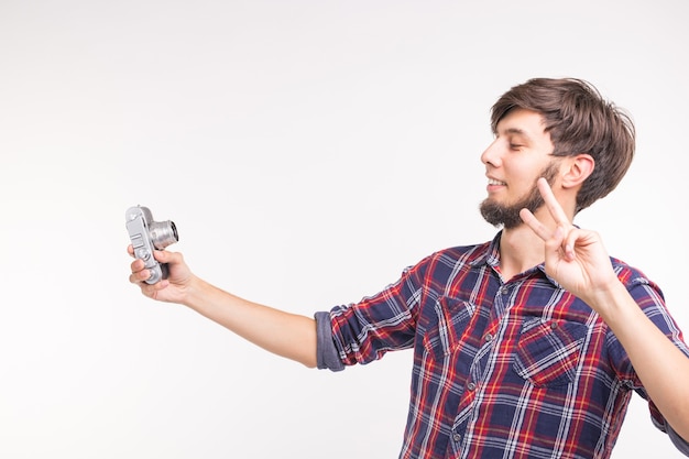 Menschen, Fotograf und Gestenkonzept - Mann mit einer altmodischen Kamera, die durch die Linse auf weißem Hintergrund schaut