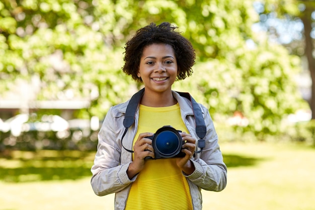 menschen, fotografie, technik, freizeit und lifestyle - glückliche junge afroamerikanische fotografin mit digitalkamera im sommerpark