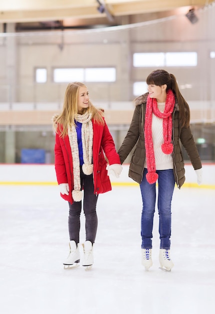 menschen, frauen, freundschaft, sport- und freizeitkonzept - zwei glückliche freundinnen auf der eisbahn