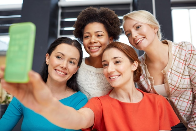 menschen-, freizeit-, freundschafts- und technologiekonzept - glückliche junge frauen, die selfie mit smartphone machen