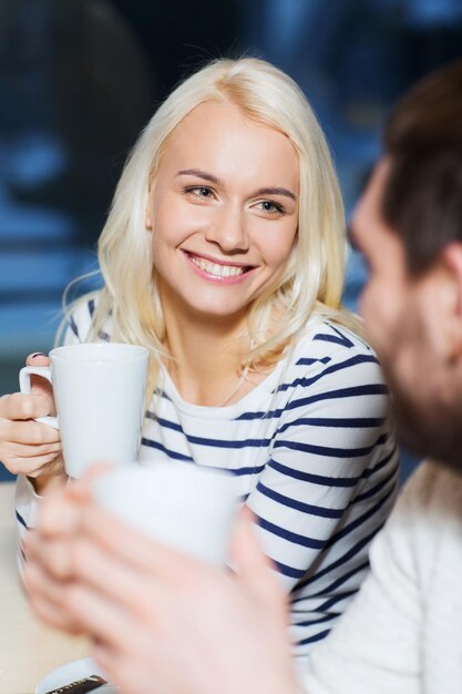 menschen, freizeit, kommunikation, essen und trinken konzept - glückliches paar trifft sich und trinkt tee oder kaffee im café