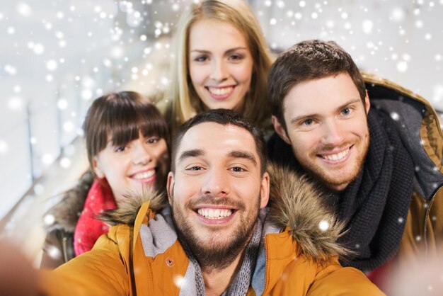 Foto menschen, freundschaft, technologie und freizeitkonzept - glückliche freunde, die selfie mit kamera oder smartphone auf eisbahn machen