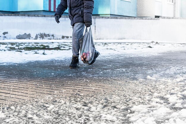 Menschen gehen auf einer rutschigen Straße aus geschmolzenem Eis Blick auf die Beine eines Mannes, der auf einem vereisten Bürgersteig geht Winterstraße in der Stadt Verletzung nach einem Sturz auf einer vereisten Straße