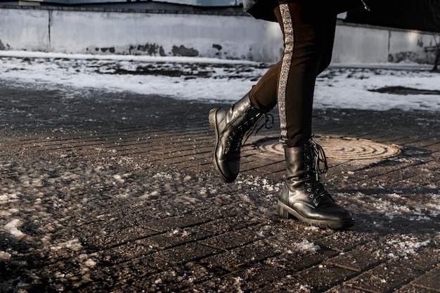 Menschen gehen auf einer rutschigen Straße aus geschmolzenem Eis Blick auf die Beine eines Mannes, der auf einem vereisten Bürgersteig geht Winterstraße in der Stadt Verletzung nach einem Sturz auf einer vereisten Straße