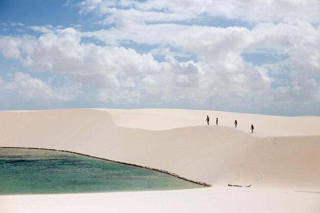 Foto menschen gehen auf sand gegen wolkigen himmel