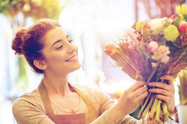 Menschen-, Geschäfts-, Verkaufs- und Floristikkonzept - glücklich lächelnde Floristin, die im Blumenladen einen Strauß macht