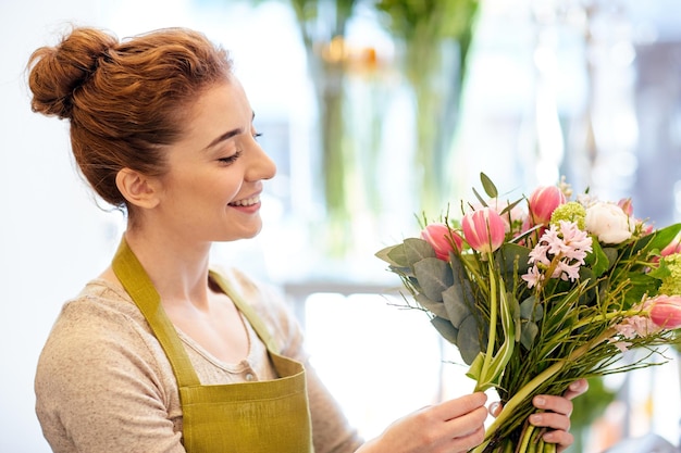 menschen-, geschäfts-, verkaufs- und floristikkonzept - glückliche lächelnde floristin, die bündel im blumenladen macht