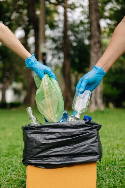 Menschen halten Müllflaschen aus Plastik und Glas in der Hand und legen sie in den Recyclingbeutel