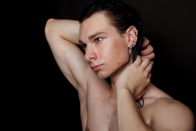 Menschen-, hautpflege- und schönheitskonzept - nasser junger mann mit langen schwarzen haaren auf einer schwarzen oberfläche