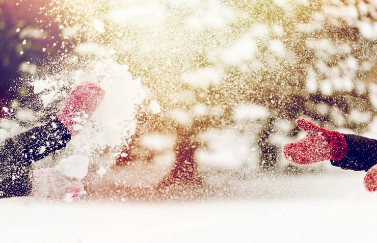Foto menschen, jahreszeit, winterferien und weihnachtskonzept - glückliche freunde, die draußen mit schnee spielen