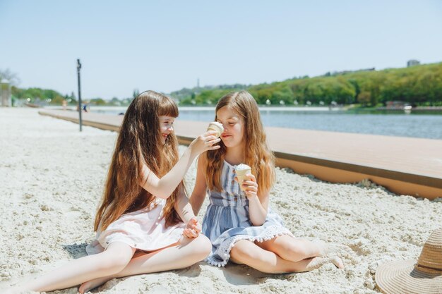 Menschen Kinder Freunde und Freundschaftskonzept Fröhliche kleine Mädchen essen Eis am Strand