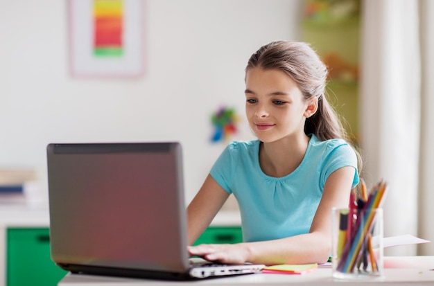 Menschen-, Kinder- und Technologiekonzept - Mädchen tippt zu Hause auf Laptop-Computer