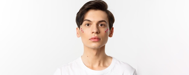 Menschen lgbtq und Schönheitskonzept Nahaufnahme eines schönen androgynen Mannes mit Glitzer im Gesicht beim Betrachten