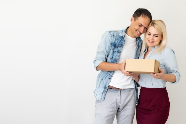 menschen, lieferung, versand und postdienstkonzept - glückliches paar, das zu hause karton oder paket öffnet