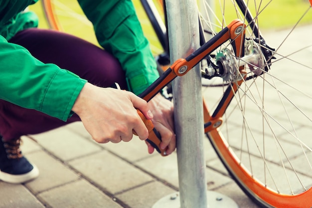 Menschen, Menschen, Sicherheit und Transport - Nahaufnahme eines Mannes, der ein Fahrradschloss auf einem Straßenparkplatz befestigt