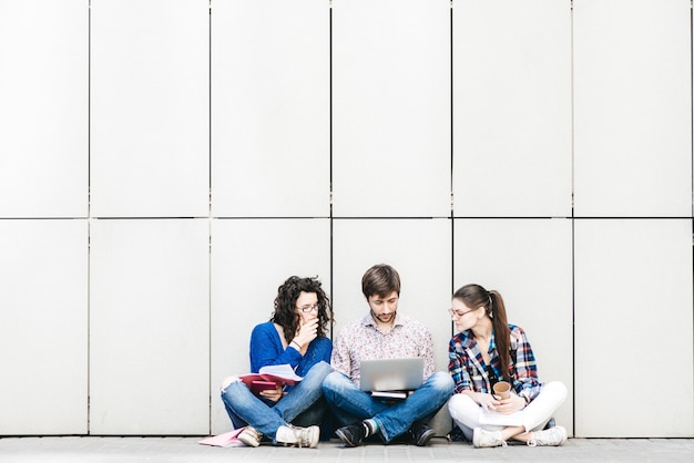 Menschen mit Bücher und Gadgets sitzen auf Boden in der Nähe der Wand. Bildung Social Media Konzept.