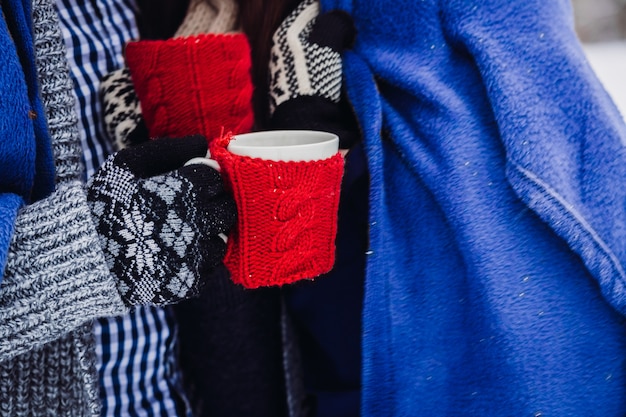 Menschen mit Wollhandschuhen und Tassen mit Stoffbezug