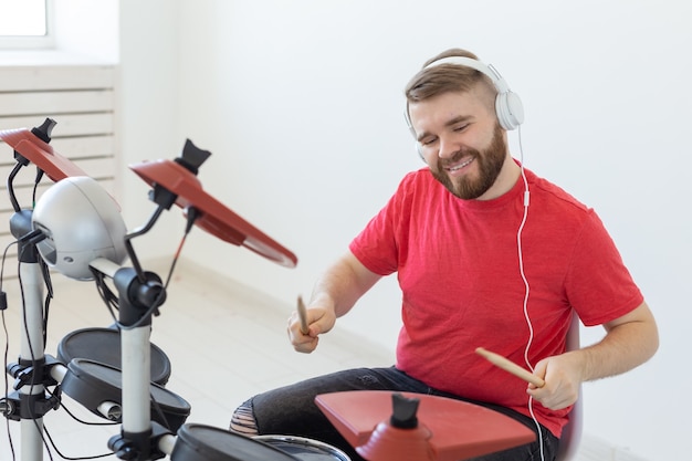 Menschen-, Musik- und Hobbykonzept - Mann spielt in seiner Freizeit das elektronische Schlagzeug.