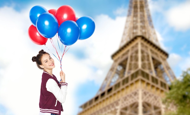 menschen-, reise-, tourismus- und urlaubskonzept - glückliches lächelndes hübsches jugendliches mädchen mit heliumballons über eiffelturm im pariser hintergrund