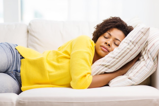 Foto menschen, ruhe, komfort und freizeitkonzept - afroamerikanische junge frau, die zu hause auf dem sofa schläft