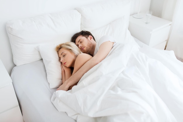 menschen, ruhe und beziehungen konzept - glückliches paar, das zu hause im bett schläft