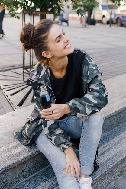 Menschen, Schönheit, Mode, Lifestyle und Farbkonzept - Ganzkörperporträt im Freien eines jungen schönen, glücklich lächelnden Mädchens, das auf der Straße posiert. Modell Blick in die Kamera. Dame in stilvoller Kleidung