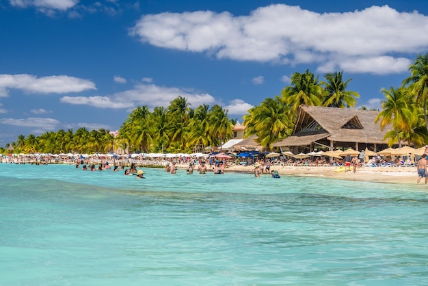 Menschen schwimmen in der Nähe von weißen Sandstrand mit Sonnenschirmen Bungalow Bar und Kokospalmen türkisfarbene Karibik Isla Mujeres Insel Karibik Cancun Yucatan Mexiko