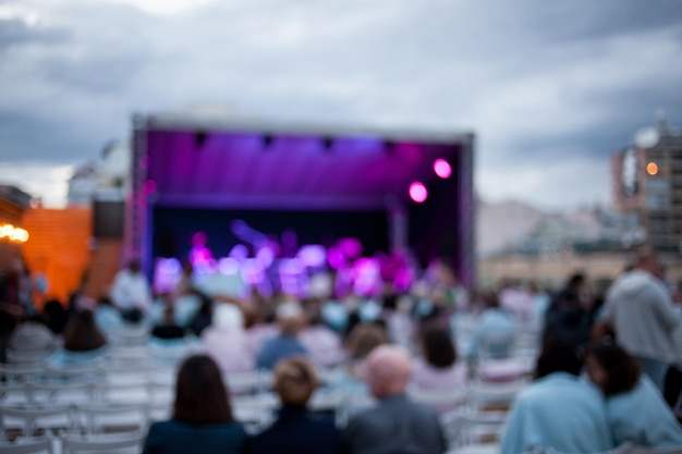 Menschen sehen sich ein Konzert mit klassischer Musik bei Tageslicht im Freien an, verschwommenes Bild