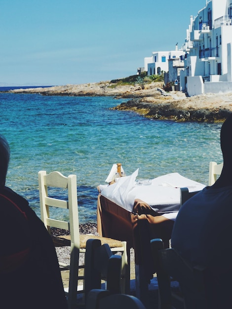 Menschen sitzen am Meer gegen den Himmel