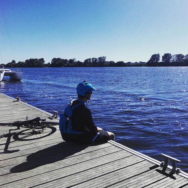 Menschen sitzen im Schwimmbad vor einem klaren blauen Himmel