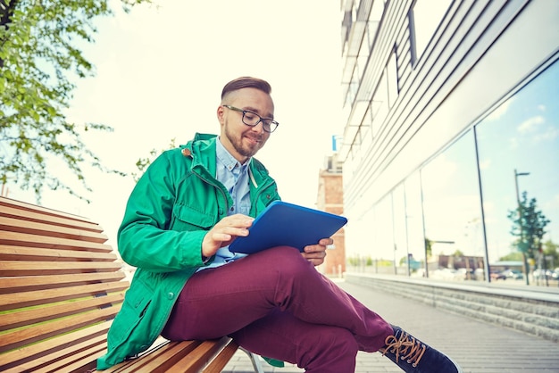 menschen, stil, technologie und lebensstil - glücklicher junger hipster-mann mit tablet-pc-computer und fixie-fahrrad, der auf einer bank in der stadt sitzt