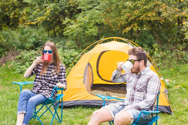 Menschen, Tourismus und Naturkonzept - Nettes Paar, das nahe gelbem Zelt sitzt