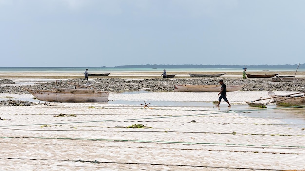 Menschen und Boote am Strand von Sansibar. Tansania