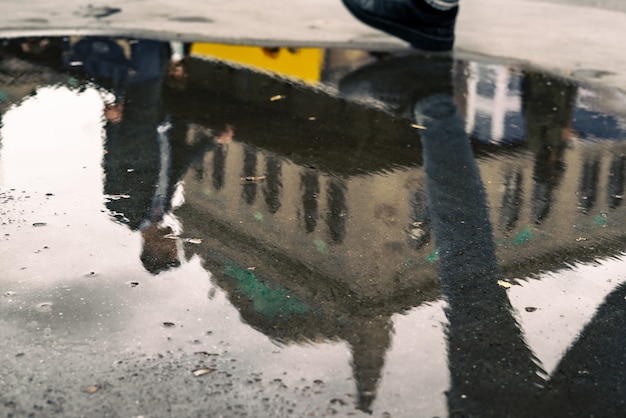 Menschen und Gebäude spiegeln sich in der Regenpfütze