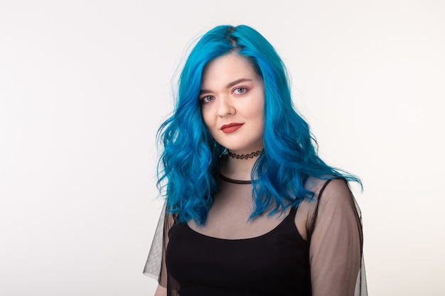 Menschen- und Modekonzept - Junge Frau mit Halsreif und blauen Haaren, die über weißer Wand aufwerfen.