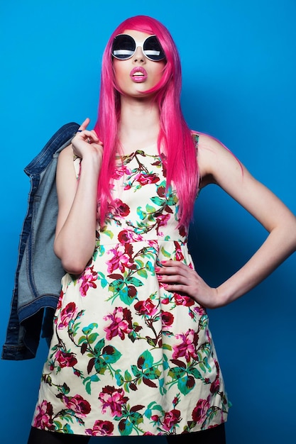 Menschen und Modekonzept Model mit rosa Haaren und großer Sonnenbrille auf blauem Hintergrund