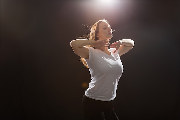 Menschen- und Tanzkonzept - Junge schöne sportliche Frau tanzt Jazz-Funk auf schwarzem Studiohintergrund.